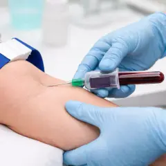 Pobieranie krwi do badań. Rękawiczki medyczne, opaska uciskowa na ramieniu i probówka z krwią.