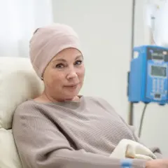 Kobieta w czepku na głowie, poddawana leczeniu, z nadzieją patrzy w przyszłość, mimo trudnych rokowań na szpiczaka mnogiego.