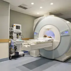 Pacjentka leży w aparacie do rezonansu magnetycznego. Obok stoi aparat do monitorowania parametrów życiowych.