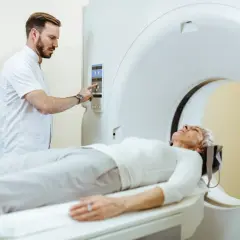 Lekarz przygotowuje pacjentkę do tomografii. Częstotliwość badań tomografem z kontrastem zależy od wskazań medycznych.