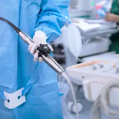Przygotowanie do echo serca przezprzełykowe: lekarz w fartuchu i rękawiczkach trzyma sondę.