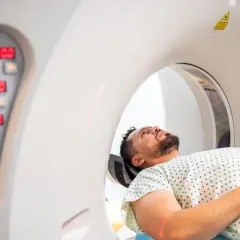 Pacjent leży w aparacie do badań RTG i rezonansu. Czerwone linie lasera wyznaczają pozycję.