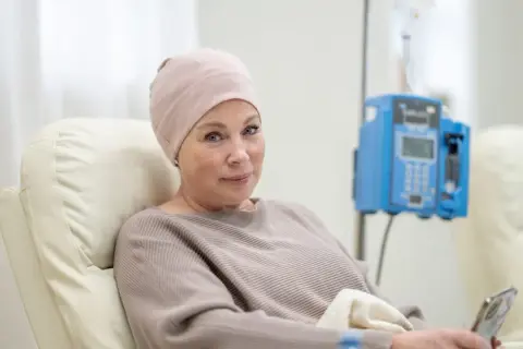 Kobieta w czepku na głowie, poddawana leczeniu, z nadzieją patrzy w przyszłość, mimo trudnych rokowań na szpiczaka mnogiego.