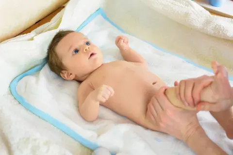 Niemowlę na ręczniku, któremu masowane są nóżki. Wczesne wykrycie krzywicy u dzieci jest kluczowe dla ich zdrowego rozwoju.