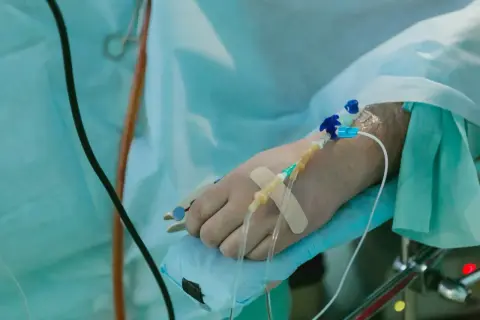 Ręka pacjenta z wenflonem i plastrem, przygotowana do podawania płynów po operacji.