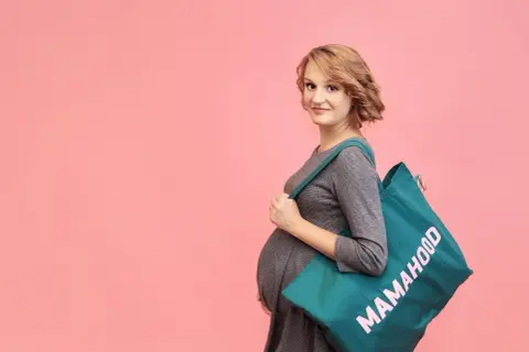 Przyszła mama z torbą "Mamahood" na ramię, gotowa na poród. Idealna torba do szpitala na operację.