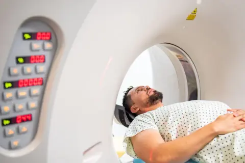 Pacjent leży w aparacie do badań RTG i rezonansu. Czerwone linie lasera wyznaczają pozycję.