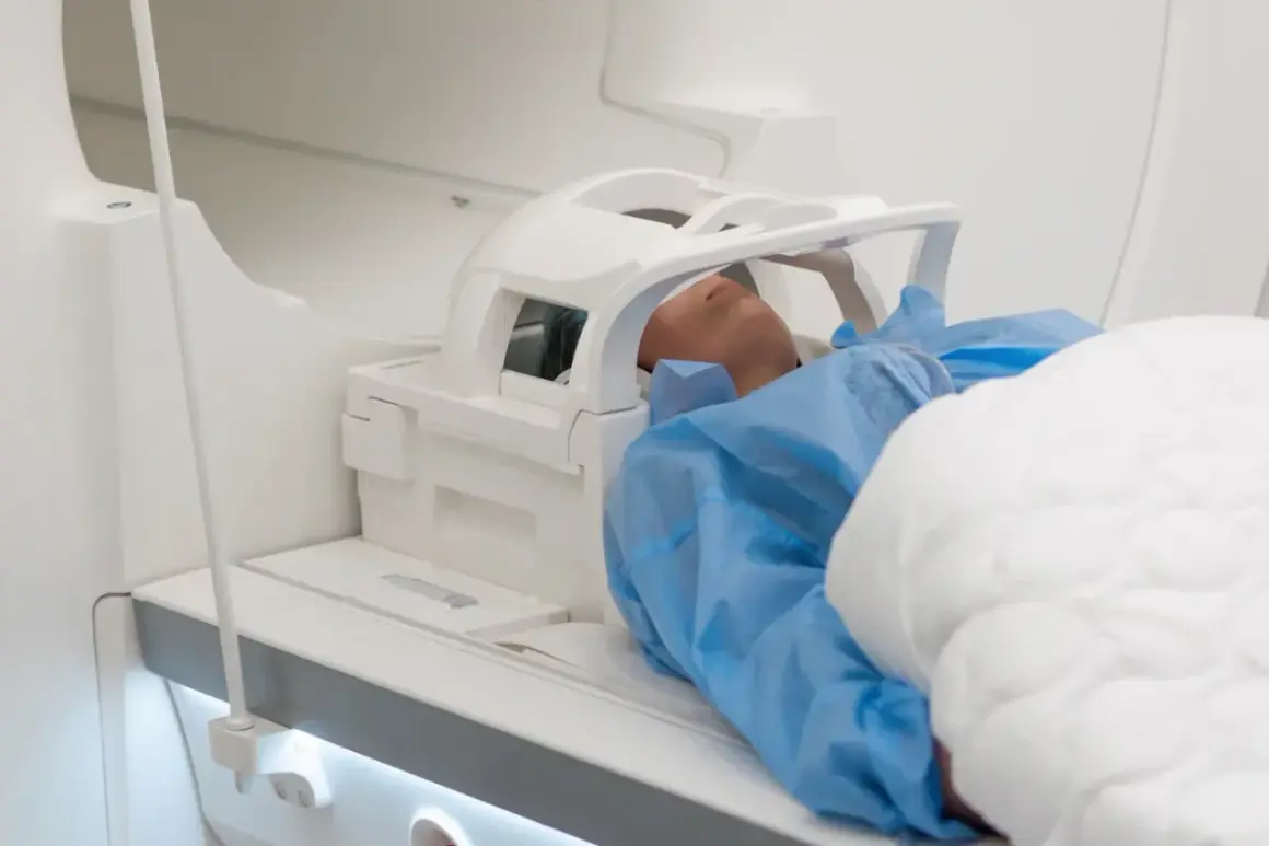 Pacjent leży w aparacie do rezonansu magnetycznego. Czy rezonans głowy obejmuje uszy? Tak, specjalna cewka jest umieszczona wokół głowy, zakrywając uszy.