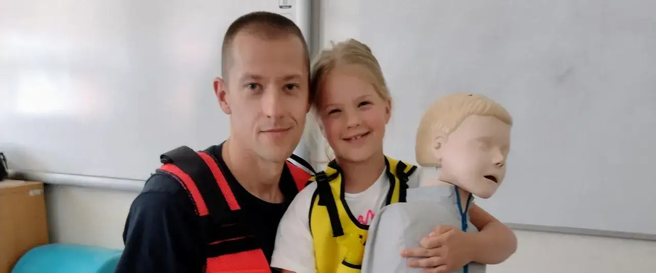 Dziecko ćwiczy pierwszą pomoc na fantomie, ucząc się, jak zareagować w sytuacji zagrożenia, np. gdy nastąpi uderzenie w skroń u dziecka.