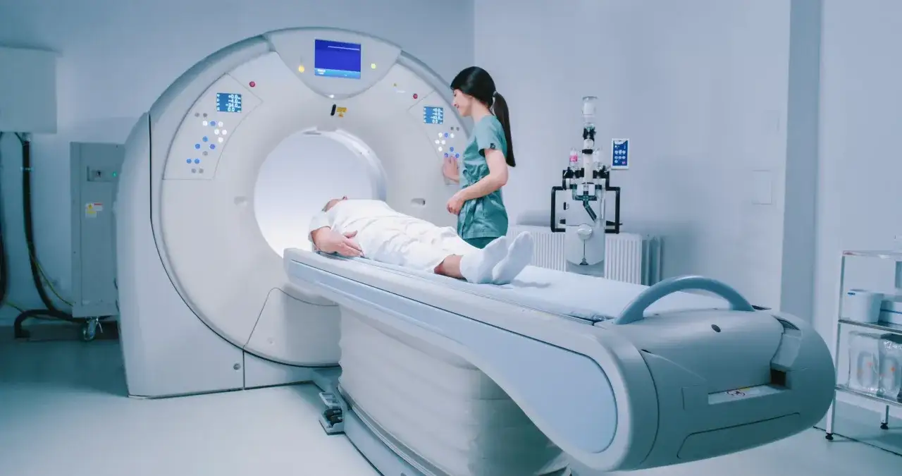 Pacjent leży na ł&oacute;żku rezonansu magnetycznego, pielęgniarka przygotowuje badanie. Szybki rezonans magnetyczny skr&oacute;t.